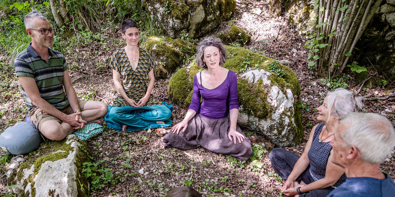 Petit groupe assis pratiquant la méditation en pleine nature