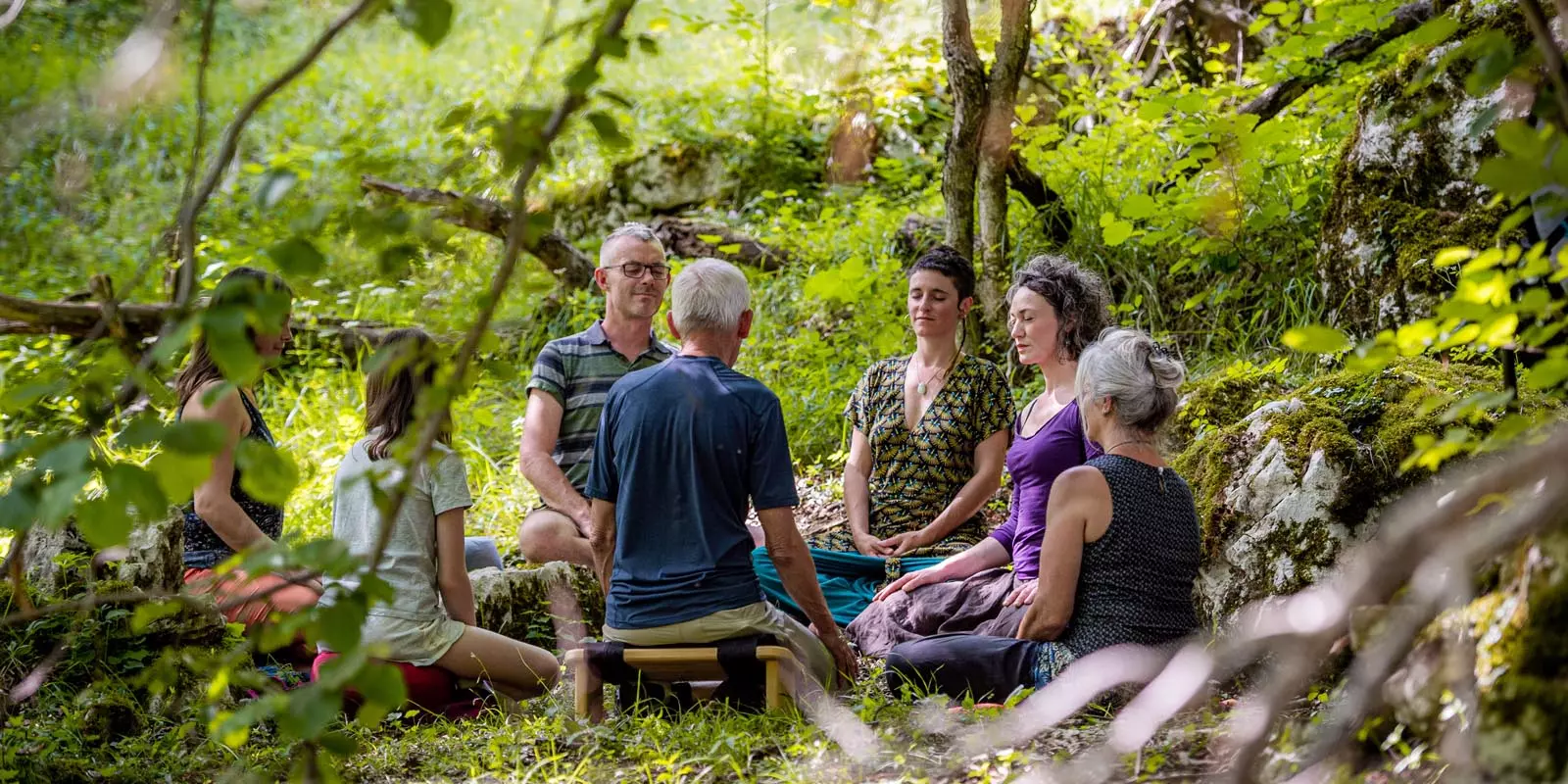 Groupe de personnes en méditation en pleine nature dans la forêt lors d'une retraite de méditation en Drôme