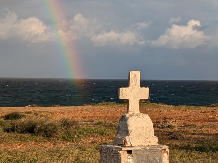 Croix au bord de la route avec un arc-en-ciel
