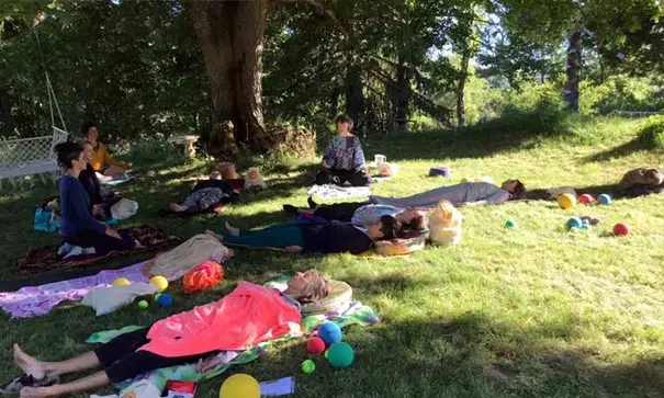 Groupe de personnes allongées sur l'herbe en posture de méditation allongée