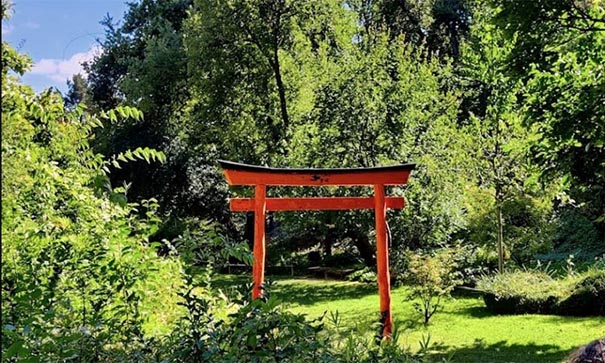 Porte rouge éclatant dans un jardin zen arboré et verdoyant
