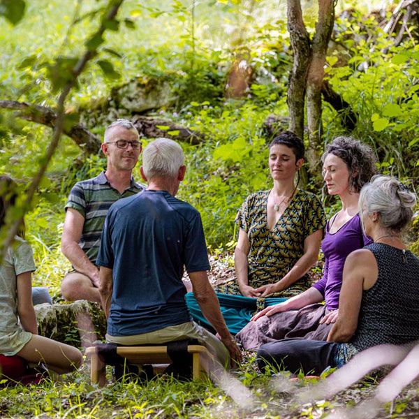 Groupe de personnes en méditation en pleine nature dans la forêt lors d'une retraite de méditation en Drôme