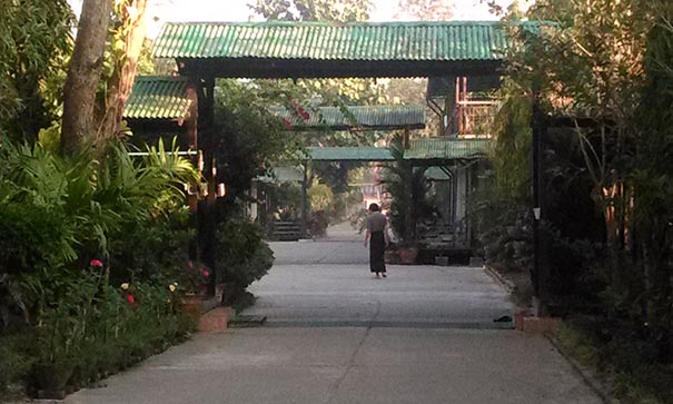 Une personne parcourt l'allée centrale du monastère Shwe Ooh Min
en Birmanie et passe sous des portiques verts