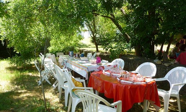 Grandes tablées sous les arbres dans le jardin extérieur pour les repas pendant le stage de méditation